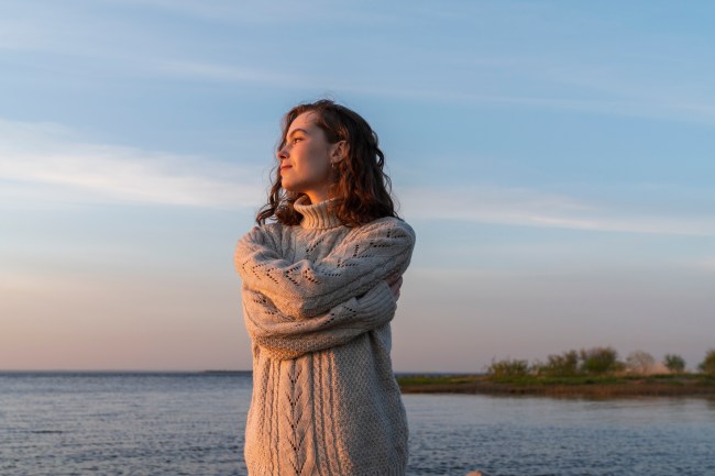 Happy woman hugging self at sunset