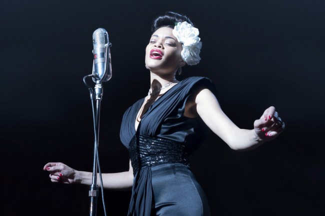 Andra Day Net Worth. Andra Day as Billie Holiday with a microphone in front of her as she is singing.