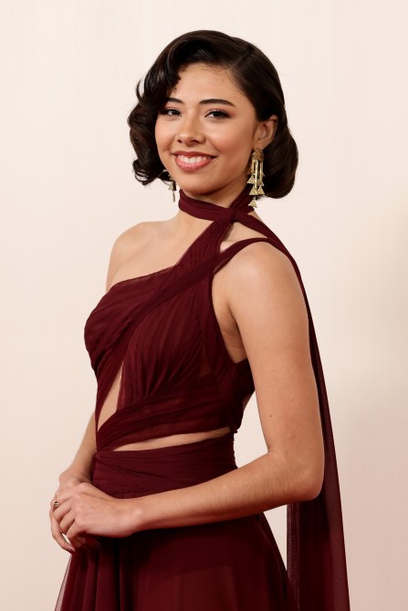 Xochitl Gomez wearing a burgundy dress her hair is curled.