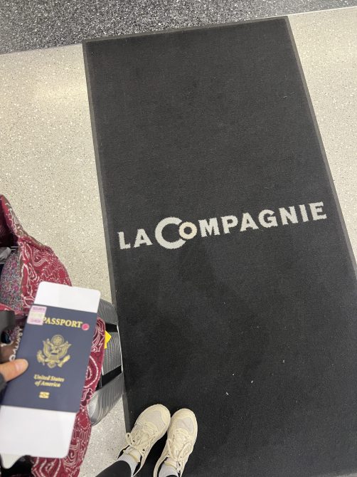 Me standing on a La Compagnie mat with my passport and carry-on in tow