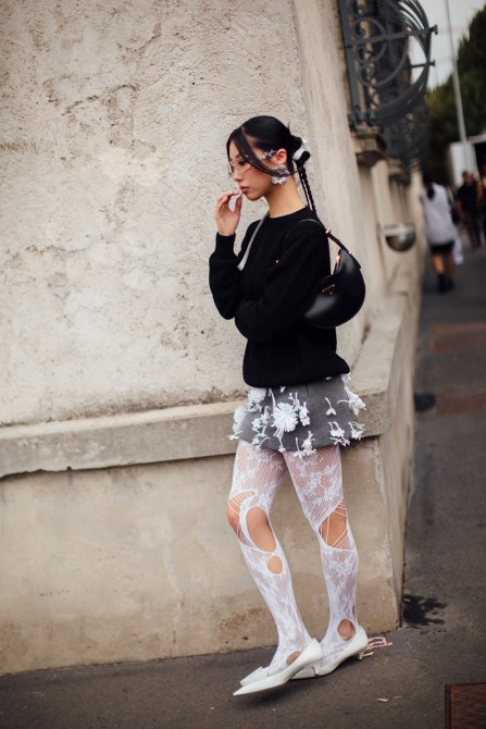 A fashion week guest wearing floral earrings.