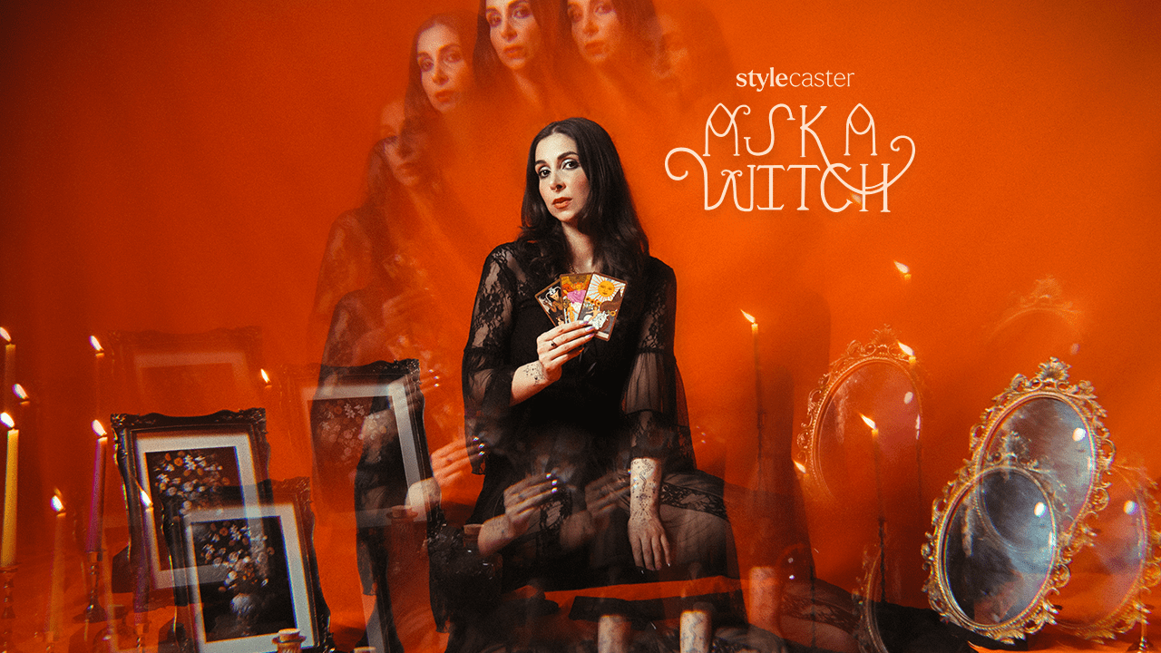 A witch woman holding up three Tarot cards, standing in front of an orange background, getting ready to give someone life-saving advice using astrology.