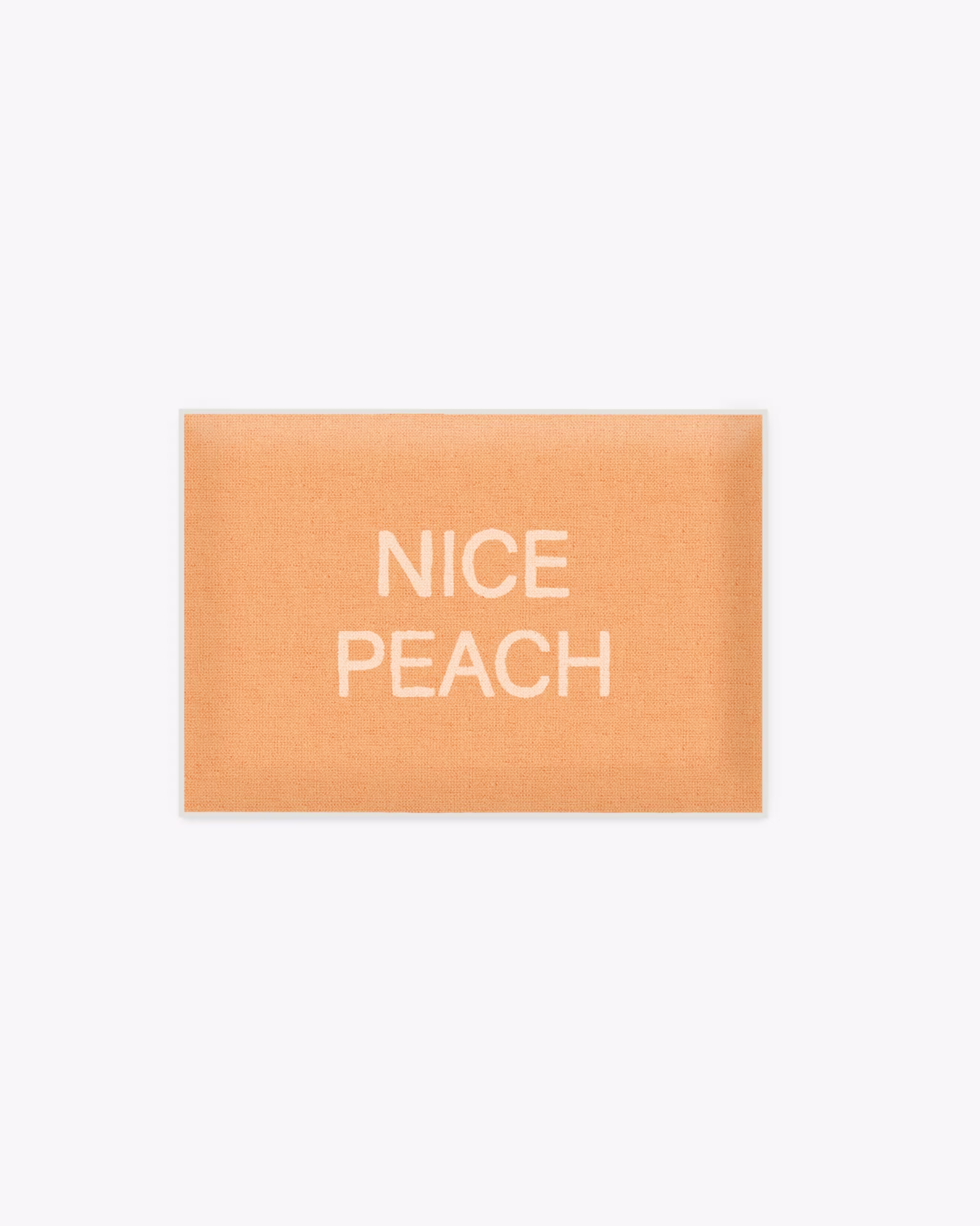 A peach-colored bath mat that says "nice peach."