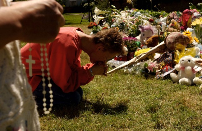 Sherry Grogan of Modesto, California prays on a lawn near a makeshift memorial as an unidentified person holds rosary beads April 19, 2003 in Modesto, California. The makeshift memorial is located outside the home where Scott and Laci Peterson lived and includes hundereds of flowers, candles and stuffed toys. Authorities have confirmed that a woman's body and fetus that washed ashore at Point Isabel in San Francisco Bay are the bodies of Laci Peterson and her unborn child, Connor. Scott Peterson, Laci Peterson's husband, has been arrested and charged with capital murder.
