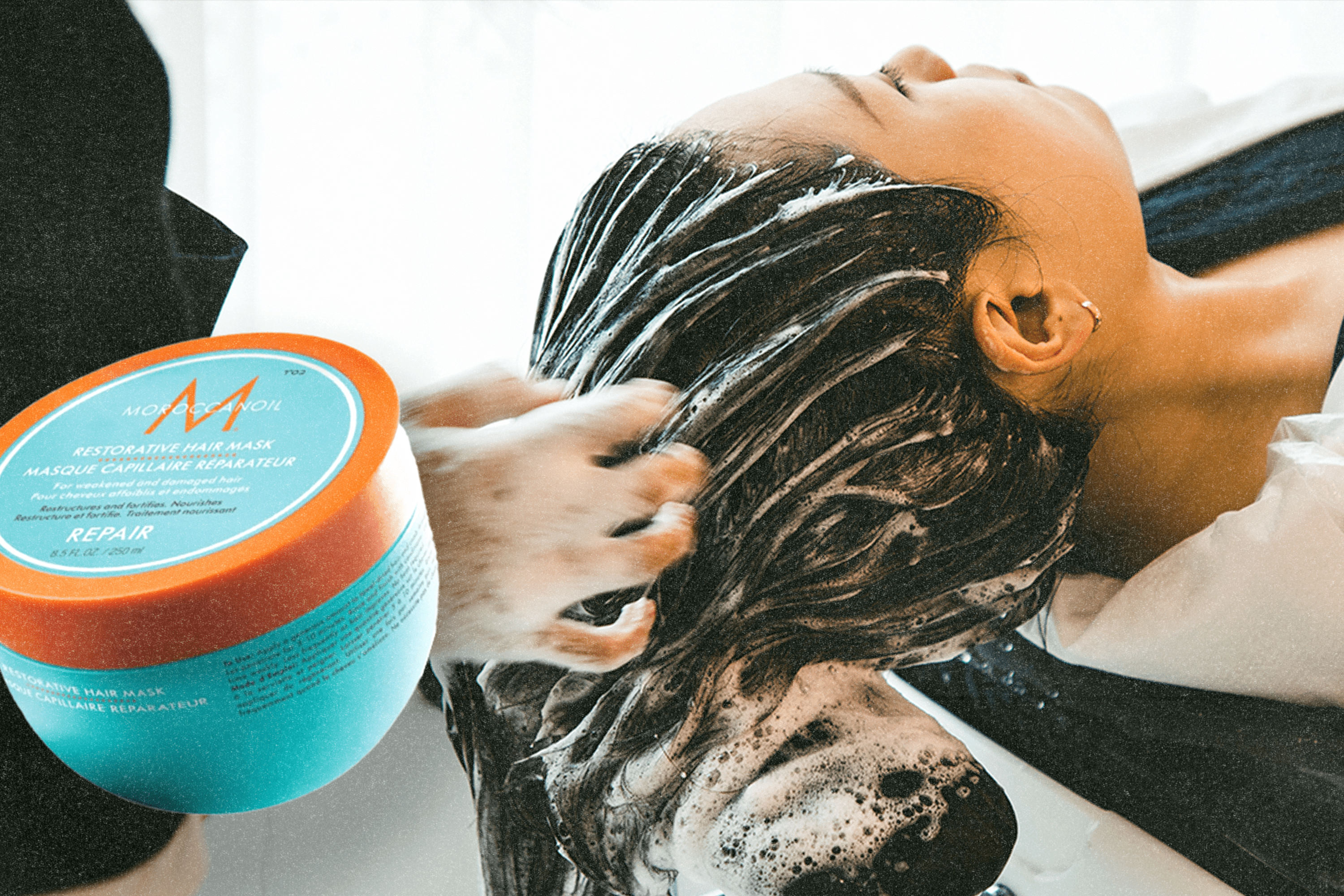 A woman putting on a hair mask next to the Moroccanoil Restorative Hair Mask.