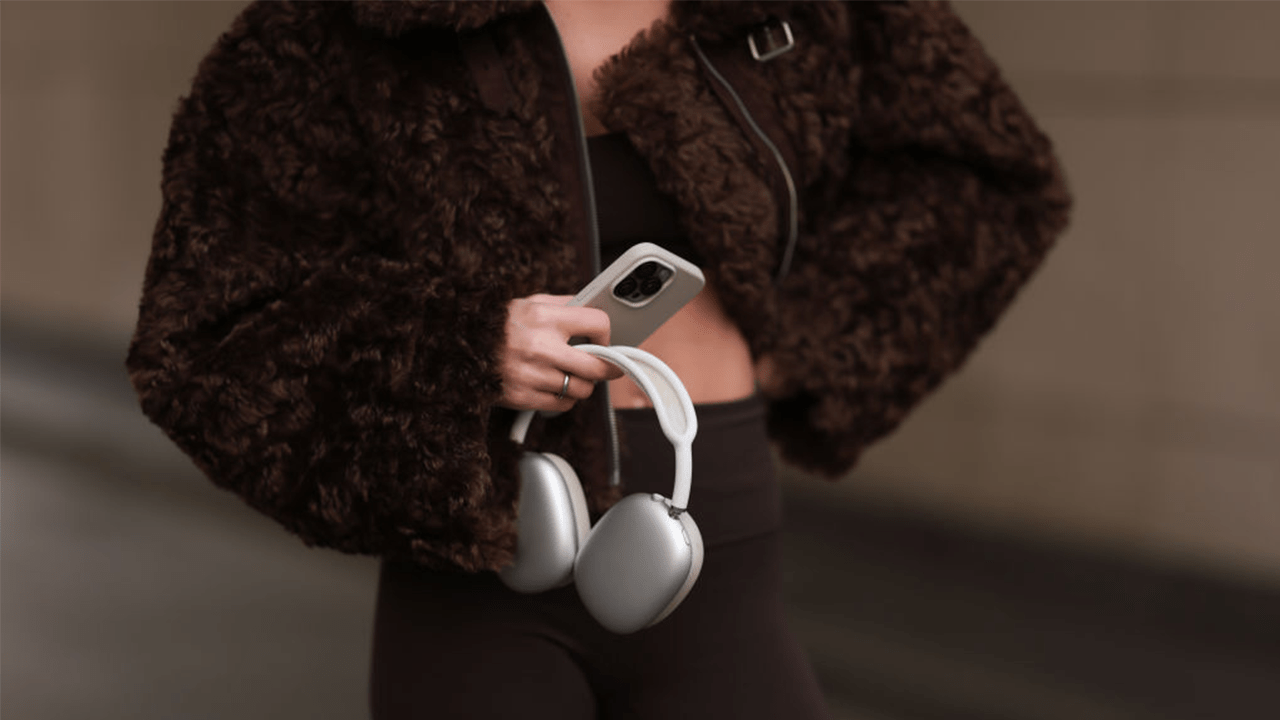 BERLIN, GERMANY - JANUARY 31: Sophia Geiss is seen wearing a cropped brown faux shearling jacket with wide sleeves from The Frankie Shop, a dark brown sports bra underneath, paired with dark brown leggings from Lululemon, and a silver ring, while holding AirPods and an iPhone during Berlin Fashion Week on January 31, 2025 in Berlin, Germany.