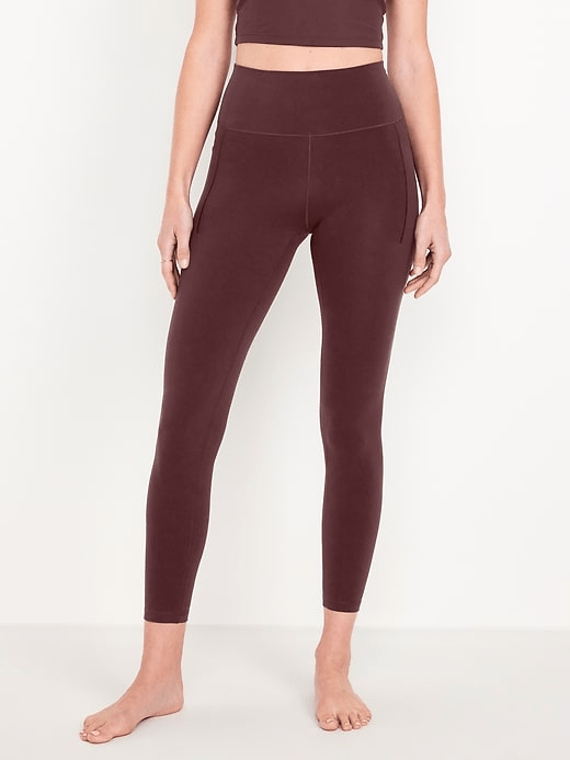 A model wearing the Old Navy Extra High-Waisted StudioSmooth 7/8 Pocket Leggings in a chocolate brown colorway