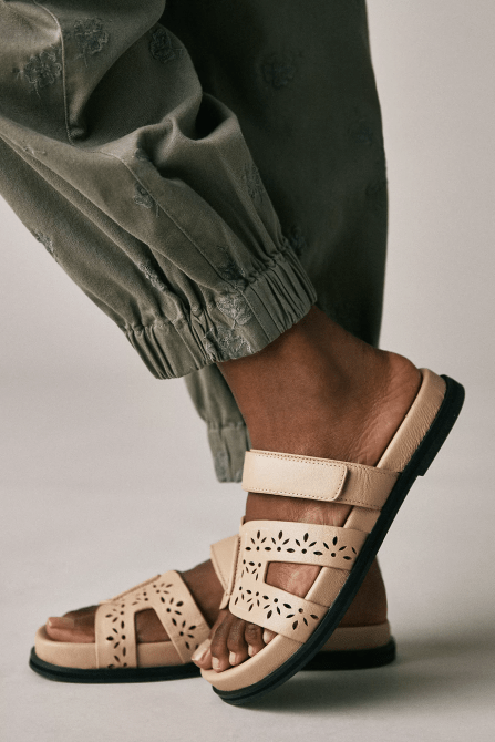 A model wearing the Bibi Lou Cutout Slide Sandals in sand