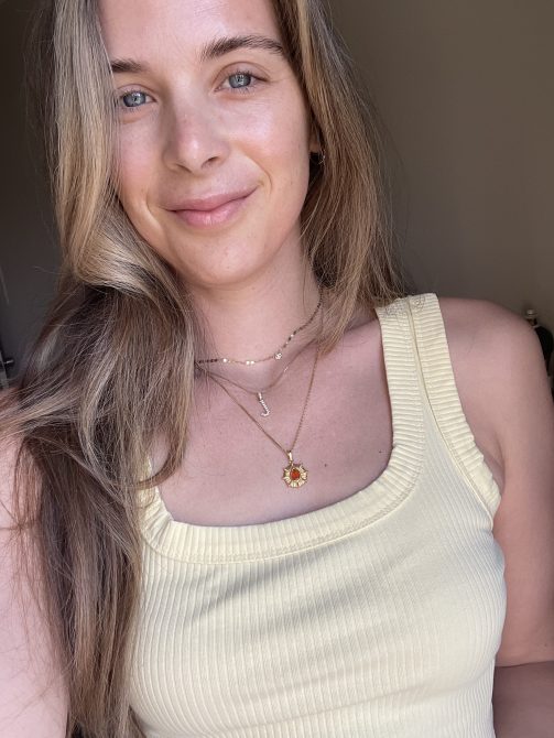 Woman in a yellow shirt with three necklaces layered together.